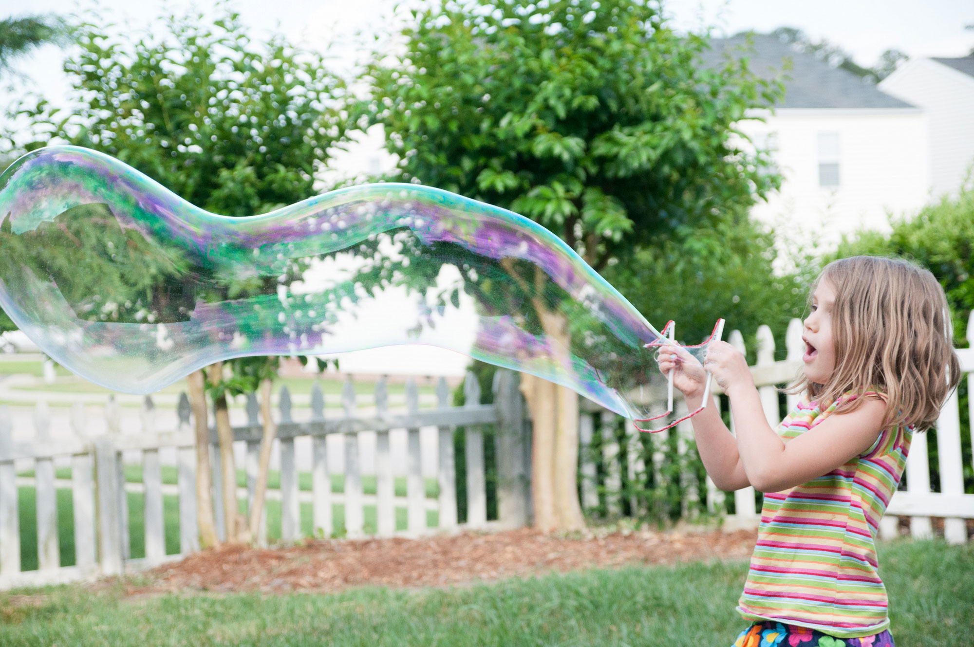 Little girl blowing giant bubbles.