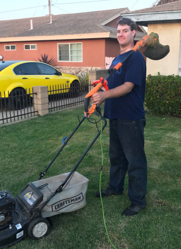 Caleb stands proudly with his lawncare gear.